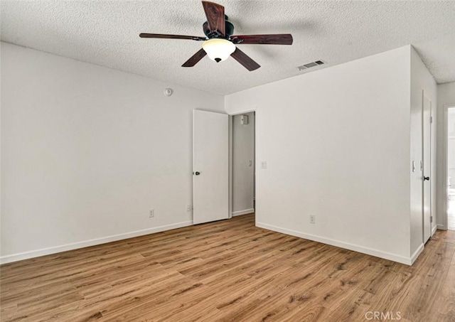 empty room with a textured ceiling, ceiling fan, visible vents, and light wood-type flooring