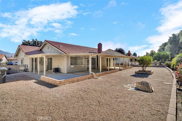 back of property with a patio, central AC, stucco siding, and a tiled roof