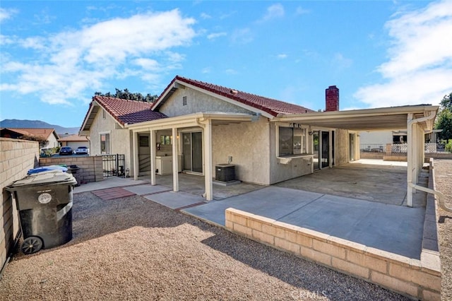 rear view of house with fence, stucco siding, and a chimney