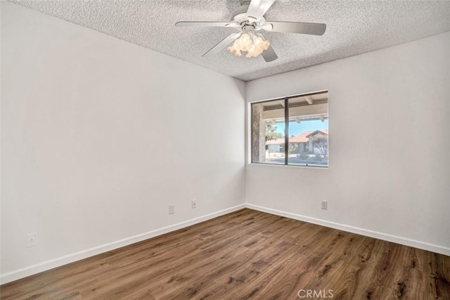 spare room featuring a textured ceiling, wood finished floors, a ceiling fan, and baseboards