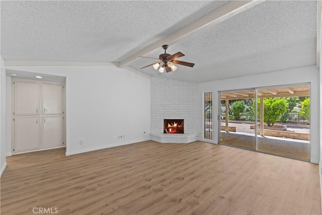 unfurnished living room with a brick fireplace, ceiling fan, light wood-style flooring, baseboards, and a textured ceiling