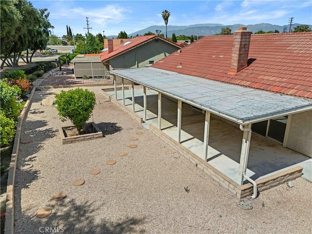 exterior space with a chimney, a mountain view, and a patio
