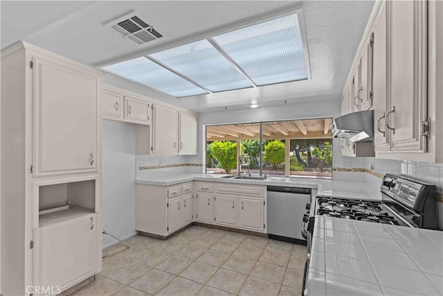 kitchen with range hood, stainless steel appliances, light tile patterned flooring, visible vents, and tile countertops