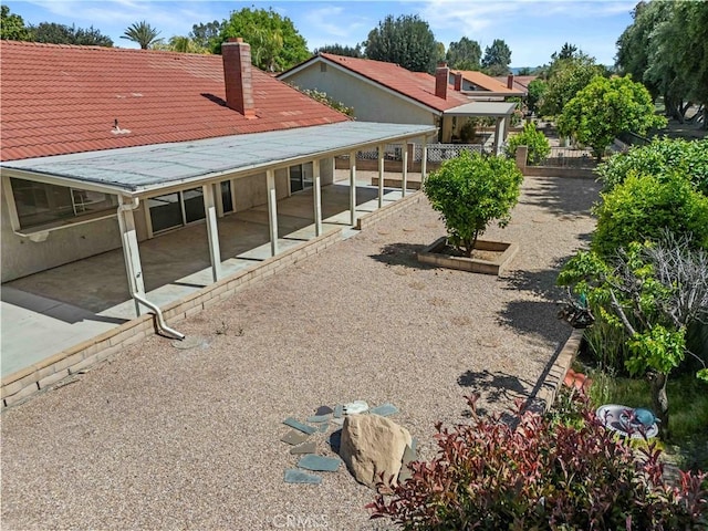back of property featuring fence, a chimney, and a patio area