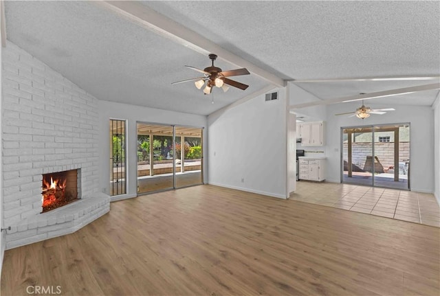 unfurnished living room with a textured ceiling, visible vents, a ceiling fan, and light wood-style floors