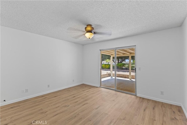 empty room with a textured ceiling, ceiling fan, wood finished floors, and baseboards