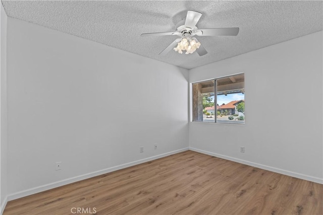 empty room featuring baseboards, wood finished floors, a ceiling fan, and a textured ceiling