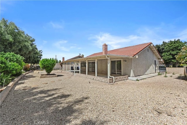 back of property with fence, stucco siding, and a chimney