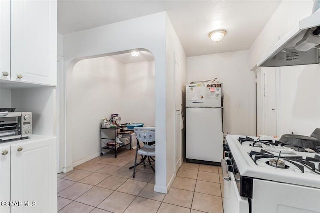 kitchen with light tile patterned floors, white cabinetry, extractor fan, and white appliances