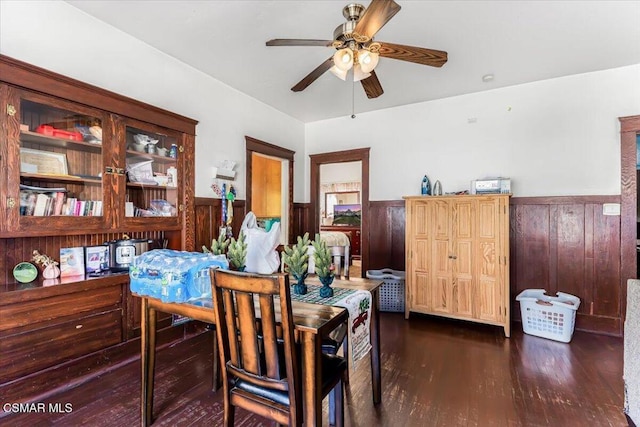 dining space with ceiling fan, dark hardwood / wood-style floors, and wooden walls