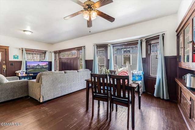 dining room with wood walls, ceiling fan, and dark hardwood / wood-style floors