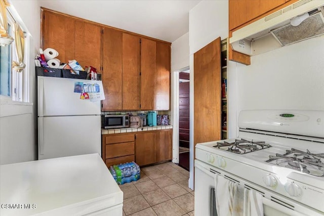 kitchen featuring light tile patterned flooring and white appliances