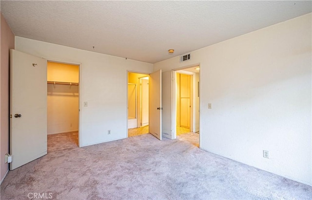 unfurnished bedroom with a spacious closet, a closet, and light carpet