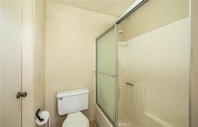 bathroom featuring toilet and shower / bath combination with glass door