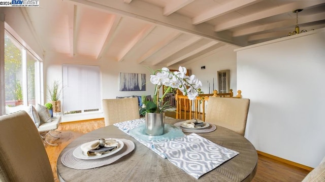 dining space featuring hardwood / wood-style floors and vaulted ceiling with beams