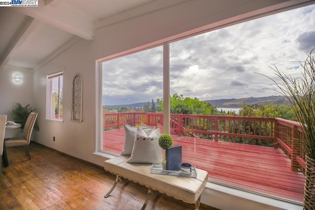 interior space with vaulted ceiling with beams, a wealth of natural light, a mountain view, and hardwood / wood-style flooring