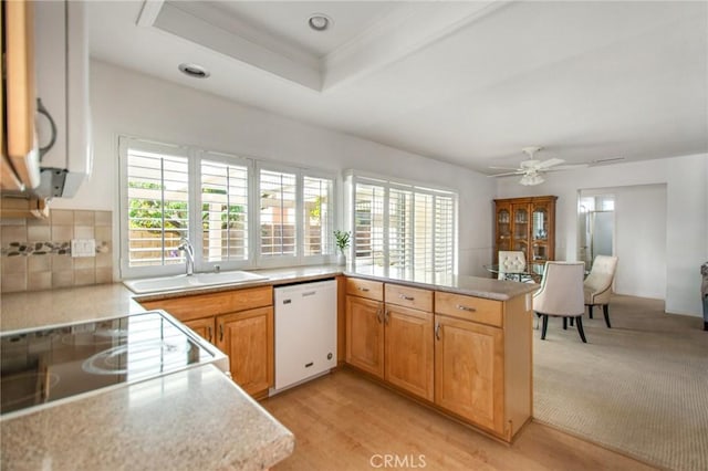 kitchen featuring a wealth of natural light, kitchen peninsula, dishwasher, and sink