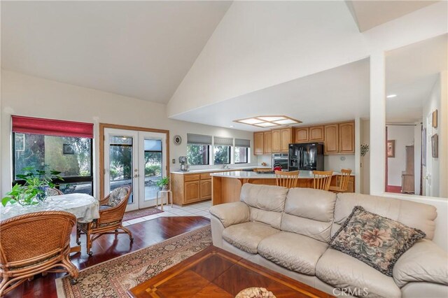 living room with high vaulted ceiling, french doors, and light hardwood / wood-style floors