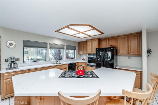 kitchen featuring a center island, black appliances, sink, a breakfast bar area, and light tile patterned floors