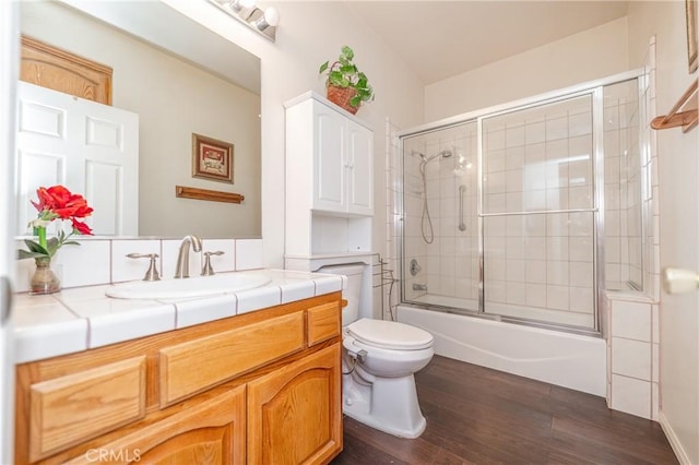 full bathroom featuring hardwood / wood-style floors, shower / bath combination with glass door, vanity, and toilet