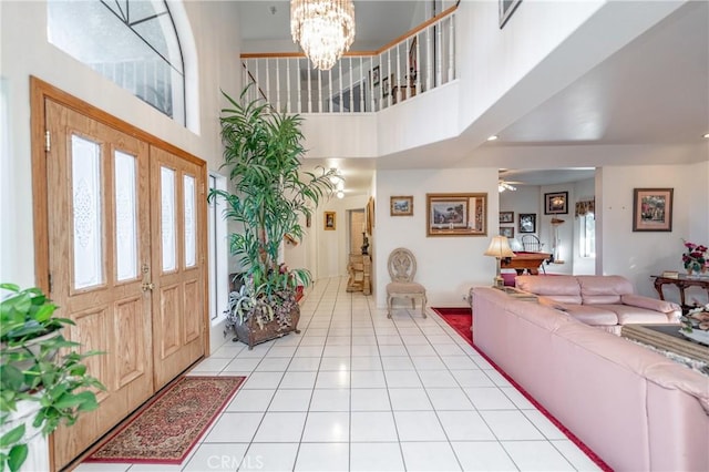 entrance foyer featuring ceiling fan with notable chandelier, a towering ceiling, and light tile patterned flooring