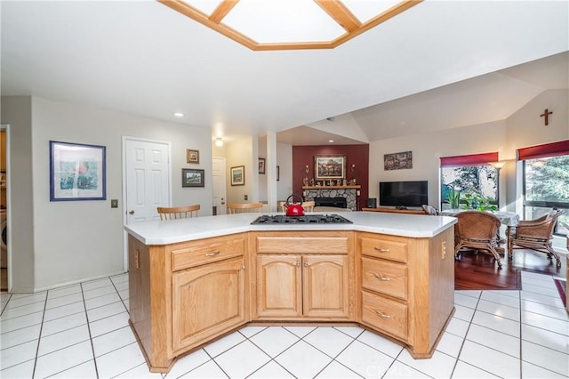 kitchen with light tile patterned flooring, lofted ceiling, light brown cabinets, and a center island