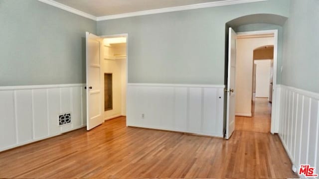 empty room with light hardwood / wood-style floors and ornamental molding