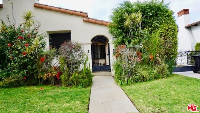 view of exterior entry featuring a lawn