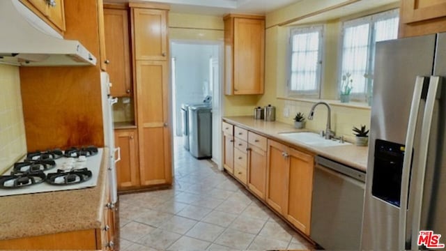 kitchen with stainless steel appliances, decorative backsplash, sink, independent washer and dryer, and light tile patterned flooring