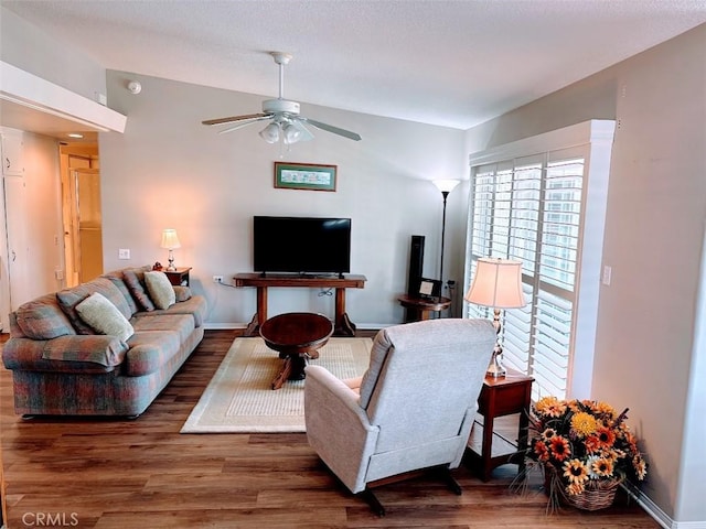 living room featuring ceiling fan, dark hardwood / wood-style floors, and vaulted ceiling