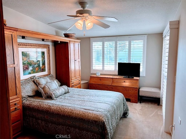 carpeted bedroom featuring ceiling fan and a textured ceiling