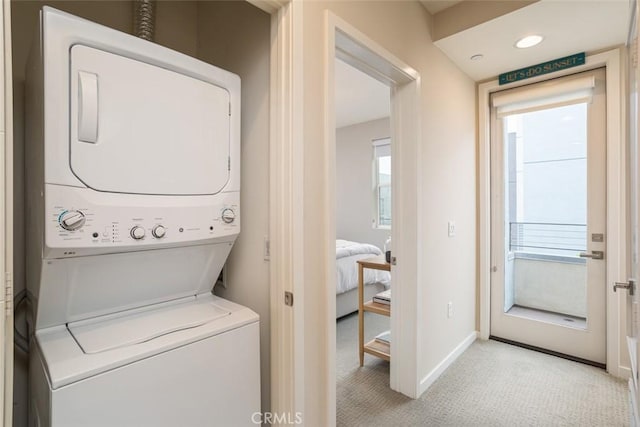 washroom featuring plenty of natural light, light colored carpet, and stacked washer / drying machine