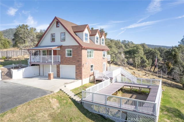 back of house featuring a lawn, a wooden deck, and a garage