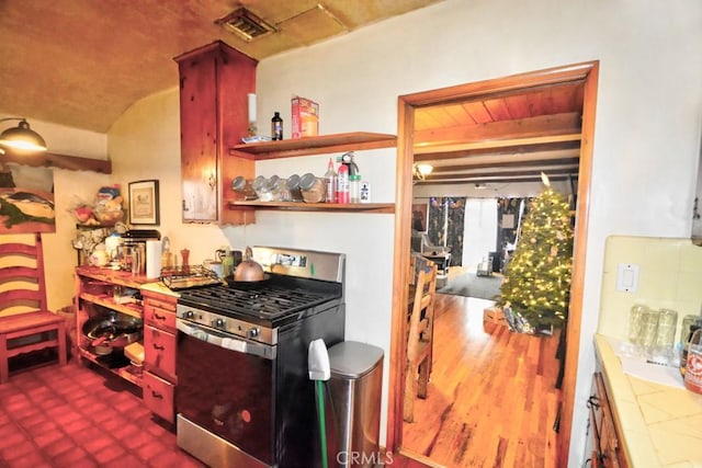 kitchen featuring stainless steel gas range, tile countertops, and decorative backsplash