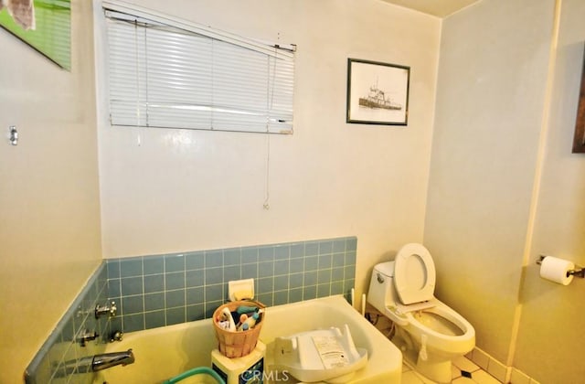 bathroom featuring tile patterned floors, a tub to relax in, and toilet