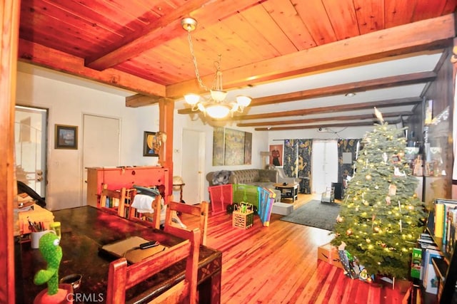 dining room with beam ceiling, an inviting chandelier, and hardwood / wood-style floors