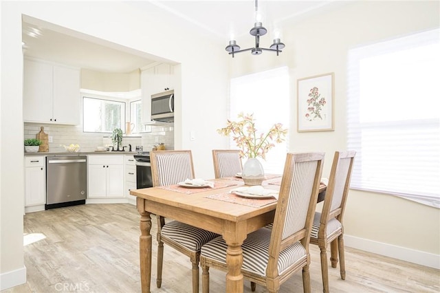 dining area featuring sink, light wood-type flooring, and an inviting chandelier