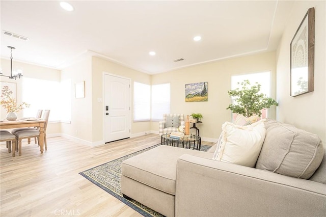 living room featuring wood-type flooring, a chandelier, and ornamental molding