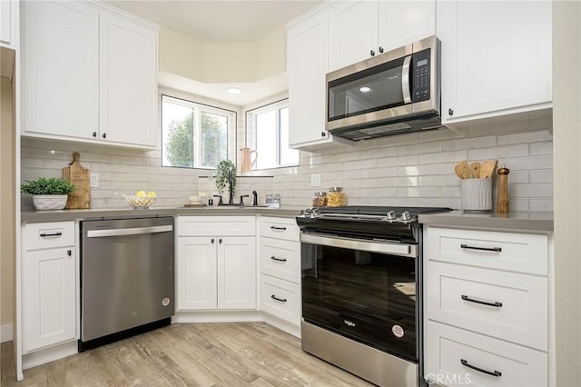 kitchen featuring stainless steel appliances, backsplash, light wood-type flooring, white cabinets, and sink