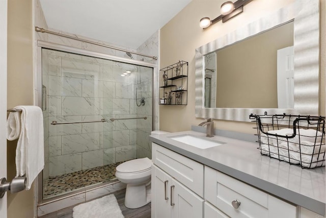 bathroom featuring wood-type flooring, vanity, toilet, and a shower with door