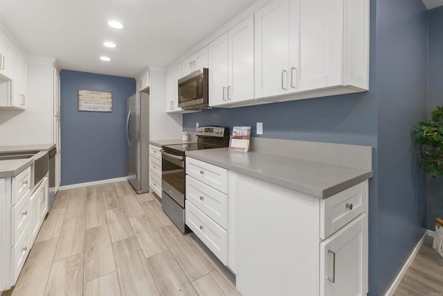 kitchen with white cabinets, stainless steel appliances, and light hardwood / wood-style flooring