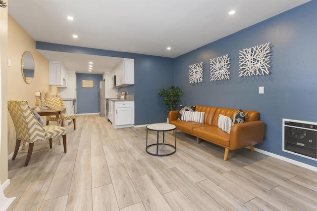 living area featuring baseboards, light wood finished floors, recessed lighting, and heating unit