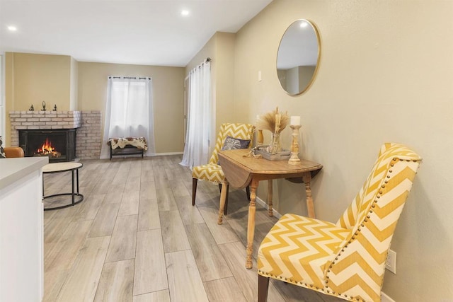 living area featuring light wood finished floors, a fireplace, and baseboards