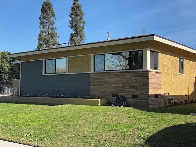 view of side of property featuring crawl space, stucco siding, stone siding, and a yard