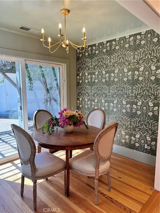 dining room with crown molding, light hardwood / wood-style floors, and a notable chandelier