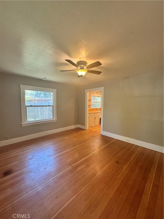 empty room with ceiling fan, plenty of natural light, and light hardwood / wood-style floors