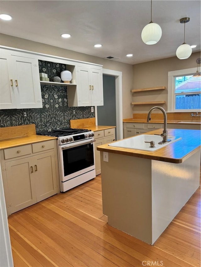 kitchen with an island with sink, high end white range oven, tasteful backsplash, pendant lighting, and white cabinets