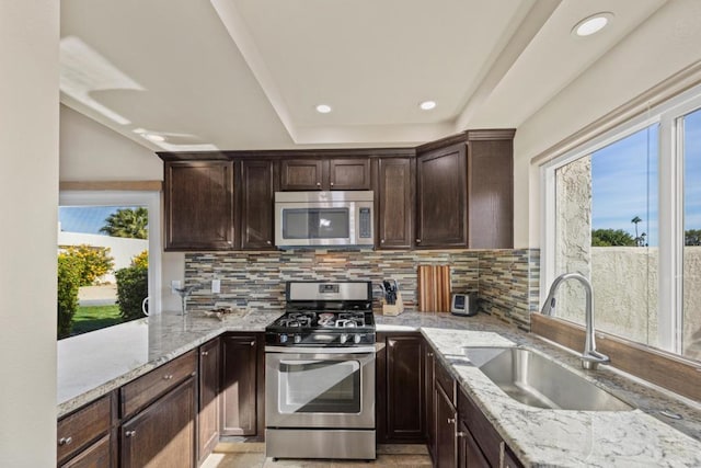 kitchen with light stone countertops, stainless steel appliances, decorative backsplash, and sink