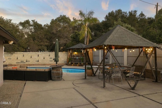 pool at dusk with a gazebo and a patio