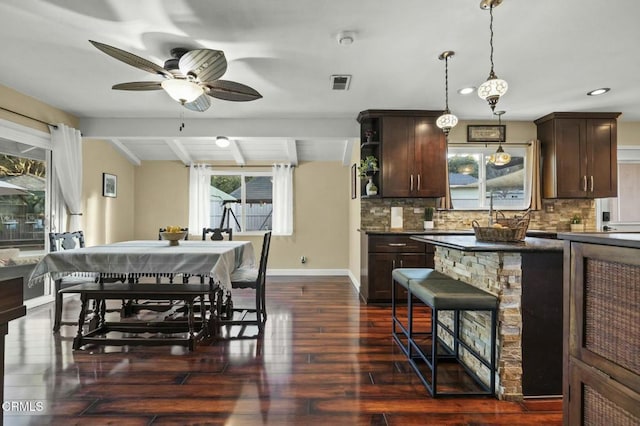 dining room featuring ceiling fan, dark wood-type flooring, and beam ceiling